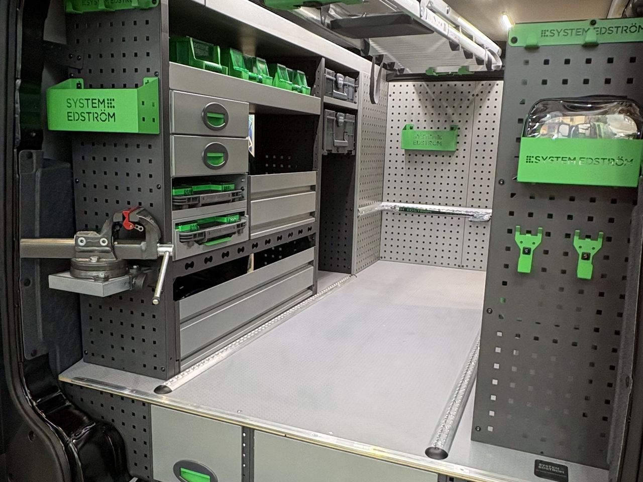 Ausgebauter Kia PV5 Cargo L2H1 in Dreiviertelansicht: Regale, Aufbewahrungsboxen und Transportschiene an der Decke